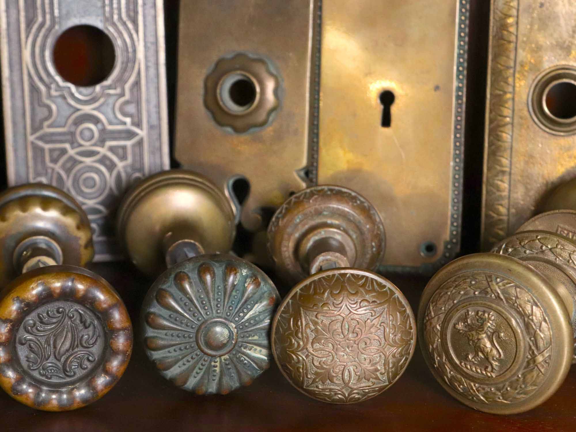 A close-up view shows intricately engraved vintage brass doorknobs and keyhole plates, their ornate patterns and craftsmanship visible in the detailed metalwork.