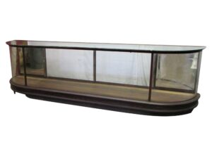 Curved glass display showcase with dark wood trim, mirrored side sections, and a long front viewing panel.