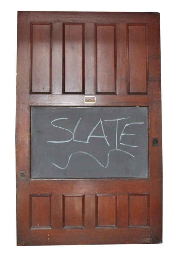 Antique wood door with paneled sections and a large central slate chalkboard panel marked with chalk.