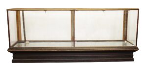 Antique glass-front retail showcase with an oak frame, clear glass panels, and a dark beveled base, shown without back doors or shelves.