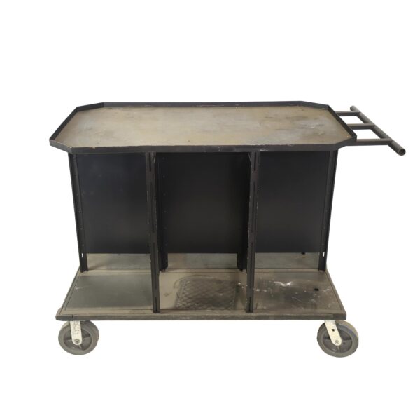 Black steel service cart with six covered sections, a push bar, and four caster wheels, shown in a front view with visible surface wear.