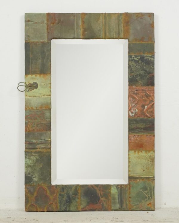 Rectangular wall mirror with a patchwork copper frame and beveled inner edge, shown front on with a mounting wire visible on the left side.