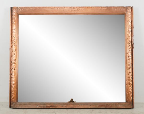 Mirror made from a salvaged copper window frame, shown front on with a wide rectangular frame and a small mounting wire visible at the bottom edge.