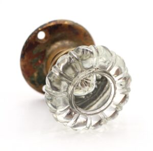 Clear fluted glass door knob with an antique brass rosette shown in close-up.