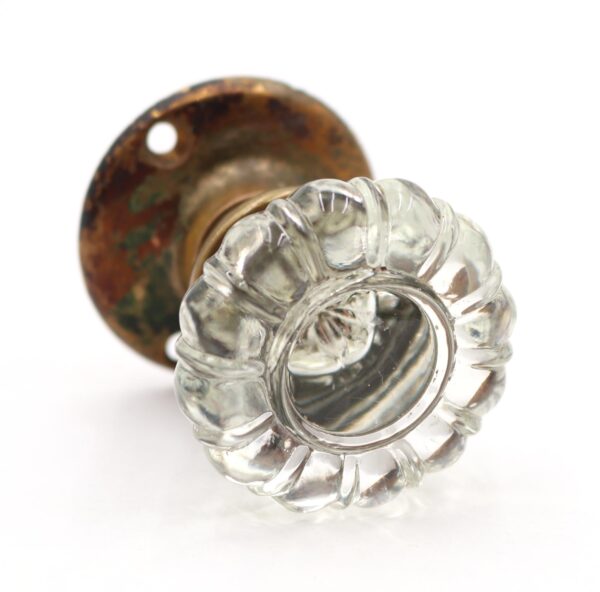 Clear fluted glass door knob with an antique brass rosette shown in close-up.