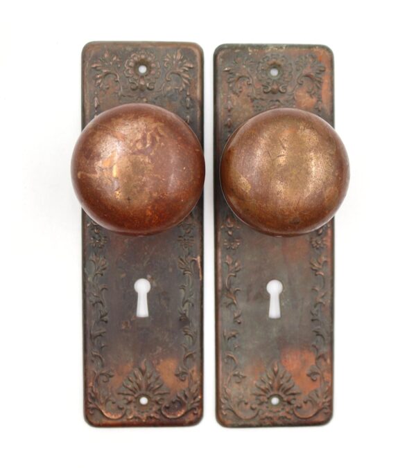 Pair of Victorian dummy door knobs with round brass knobs and ornate back plates, shown front view with keyhole openings and surface wear from use.