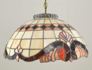Tiffany-style pendant light with a stained glass shade in cream, amber, and orange floral and geometric sections, shown hanging from a chain with a brass canopy.