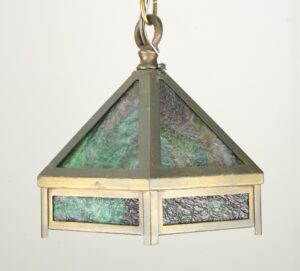 Arts & Crafts hexagonal pendant light with marbled green slag glass panels and antique brass framing, shown hanging from a steel chain.