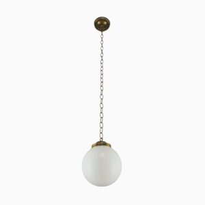 Schoolhouse pendant light with an opaline glass globe, antique brass chain, and round ceiling mount.