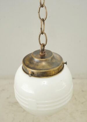 Schoolhouse pendant light with a milk glass globe and antique brass chain fitter.