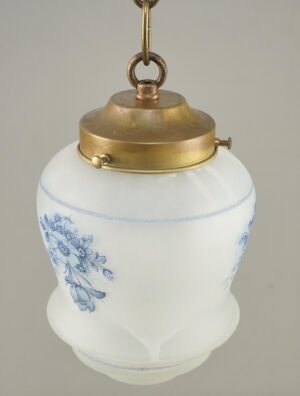 Pendant light with a white glass globe, blue floral pattern, and antique brass fitter and chain.