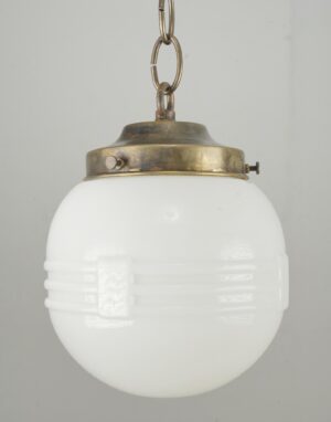 Schoolhouse pendant light with a milk glass globe and antique brass fitter hanging from a chain.