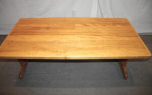 Vintage wooden coffee table with a rectangular top and trestle base, shown at a slight angle.