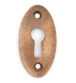 Vintage brass oval keyhole cover plate with a textured surface and centered keyhole opening, shown front view with two screw holes.