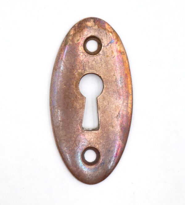 Vintage brass oval keyhole cover plate with two screw holes and a central keyhole opening.