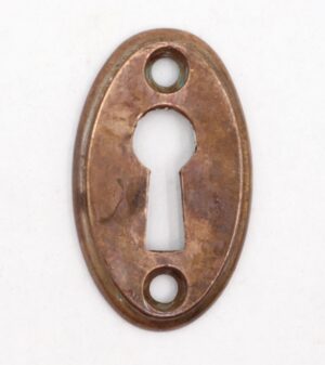 Vintage brass oval keyhole cover plate with two screw holes and a centered keyhole opening.