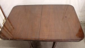 Top view of a Regency Revival drop leaf dining table with the leaves raised, showing the dark wood tone and visible surface wear.