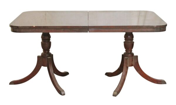 Regency Revival drop leaf dining table in dark wood tones with a rectangular top, turned pedestal supports, and curved three-legged bases.