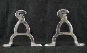 Pair of chrome butcher rack hook brackets shown side by side, with curved mounting feet and worn surface finish visible on each piece.