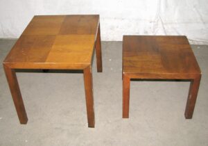 Pair of mid-century nesting side tables in a medium wood tone, shown together with checkerboard parquet tops and straight block legs.