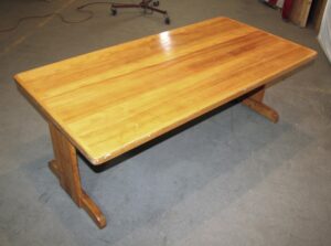 Vintage wooden coffee table with a glossy rectangular top and trestle base, shown in a three-quarter view.