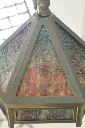 Hexagonal pendant light with brass framing and marbled green glass panels, shown in close-up from below.