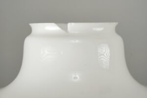 Close-up of a milk glass schoolhouse pendant light with a visible chip on the rim.