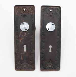 Pair of Victorian dummy door plates with round knobs and ornate back plates, shown front view with keyhole openings and surface wear.