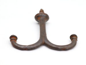 Vintage cast iron double arm ceiling mount hook with a screw top and two curved arms, shown in a close-up view with visible surface wear and rust.