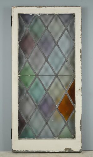 Tudor-style casement window with a diamond leaded stained glass panel, white-painted steel frame, and visible surface wear, shown with the original hinges attached.