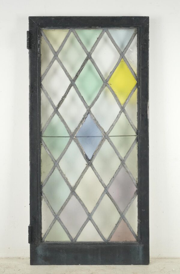 Tudor-style casement window with a leaded diamond stained glass pattern in pastel colors and a black-painted steel frame.