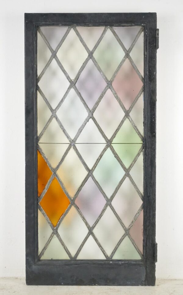 Tudor-style stained glass casement window with a leaded diamond pattern, black steel frame, and pastel multi-color panes, shown with the hinges on the right side.