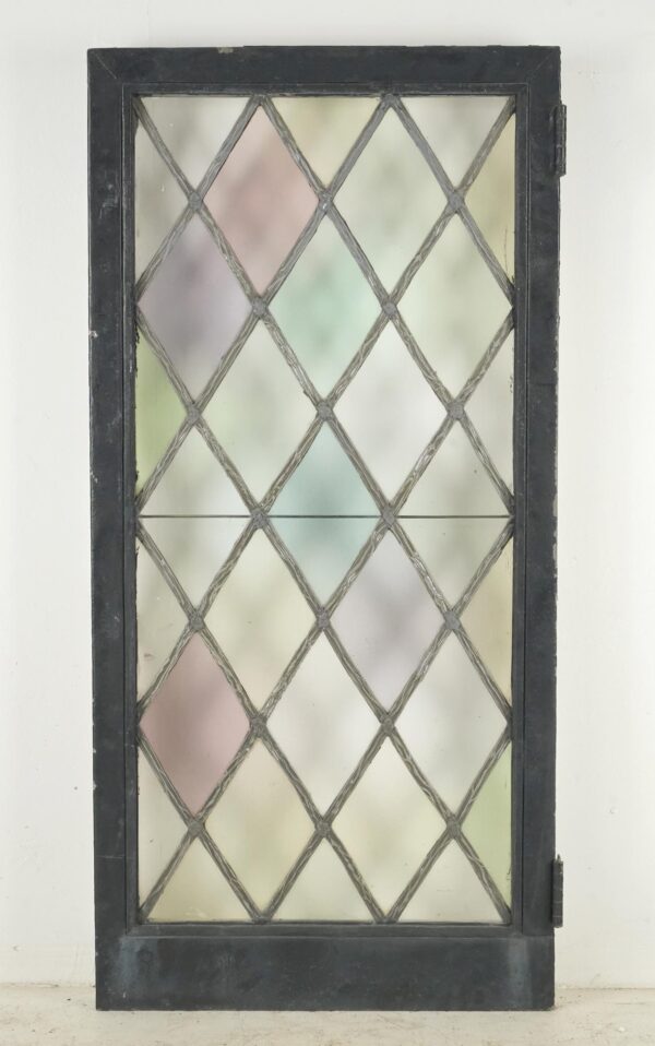 Tudor-style casement window with a leaded diamond stained glass pattern, black-painted steel frame, and visible hinges.