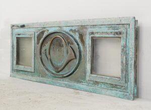 Antique bronze window panel with verdigris finish, two side glass panes, and a central post horn relief.