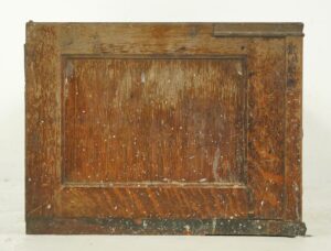 Single antique oak cabinet front with worn finish and brass hardware detail on a lower panel.