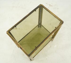 Vintage side table with a polished brass frame and smoked glass top, shown at an angle to reveal the rectangular form and lower support leg.