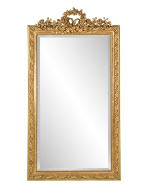 Rectangular wall mirror with an ornate giltwood frame and carved floral crest at the top, showing visible age spots on the glass.