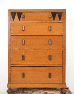 Five-drawer oak dresser with geometric top drawer inlays and dark handles, shown front view on turned feet.
