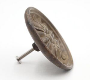 Round brass drawer pull shown at an angle with a floral design and mounting screw attached.