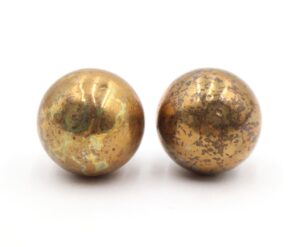 Pair of brass ball-shaped cabinet knobs shown side by side, each with a polished finish and heavy surface wear.