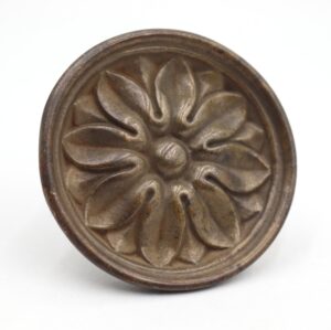 Round floral drawer pull in antique brass with a raised petal design and worn surface, shown front on.