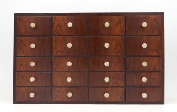 Mid century wall cabinet with twenty small drawers in a four-by-five grid and round brass knobs.