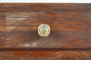 Close-up of a brass drawer knob on the dark wood cabinet front.