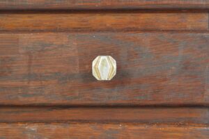 Close-up of a brass knob on the dark wood cabinet front.