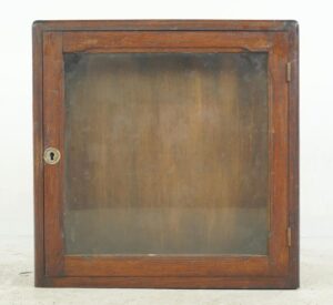 Vintage industrial cabinet with a dark wood frame, glass front, and brass keyhole hardware shown from the front.