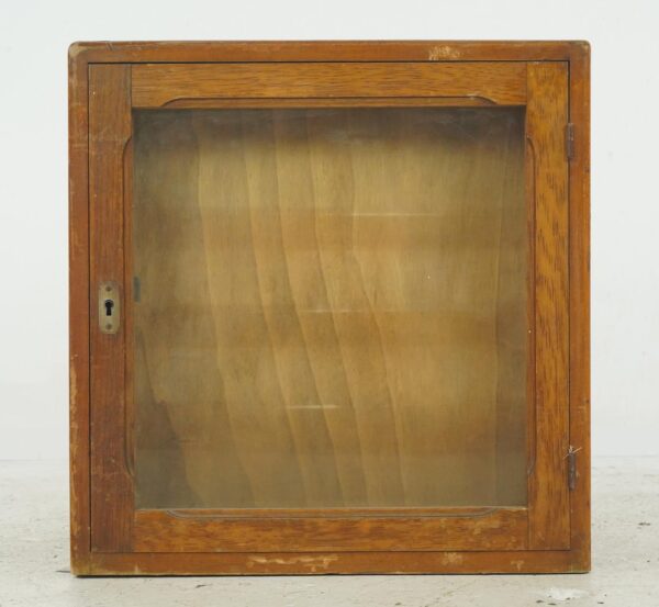 Vintage display cabinet with a glass front, medium wood tone frame, and brass keyhole hardware.