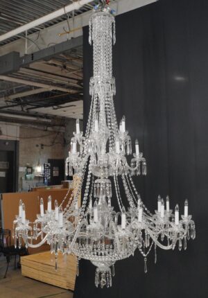 Tall crystal chandelier with multiple candle-style lights and hanging prisms, shown full length.