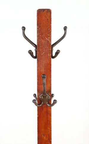 Antique coat rack with a dark wood pole and metal hooks, shown in close-up with two of the upper hooks and one lower hook visible.
