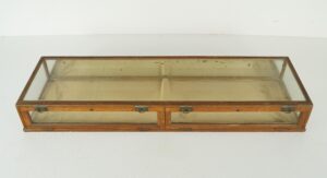 Vintage collector’s display case with a dark wood frame, clear glass panels, and a mirrored back, shown with the front access panels closed and brass hardware visible.