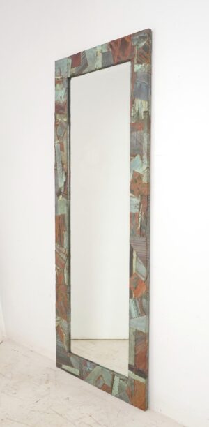 Tall dressing mirror with a handcrafted collage frame made from reclaimed copper roofing, showing verdigris and muted red tones around a beveled mirror.